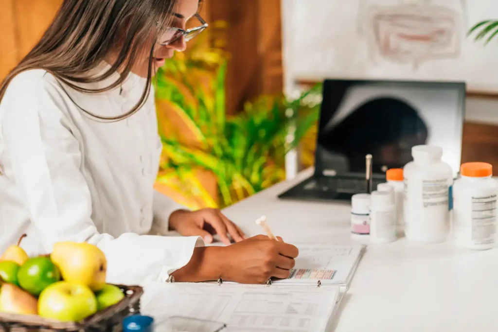 Woman reviewing health supplements and notes at a desk.